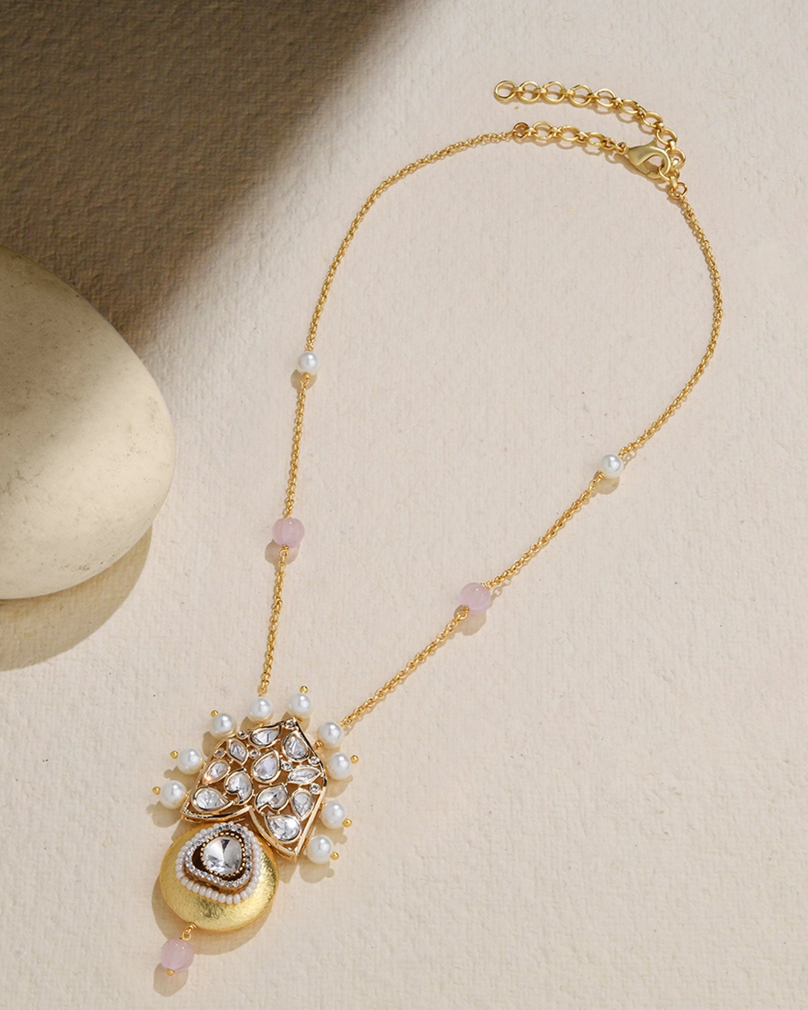 golden necklace featuring a pendant with a pearl