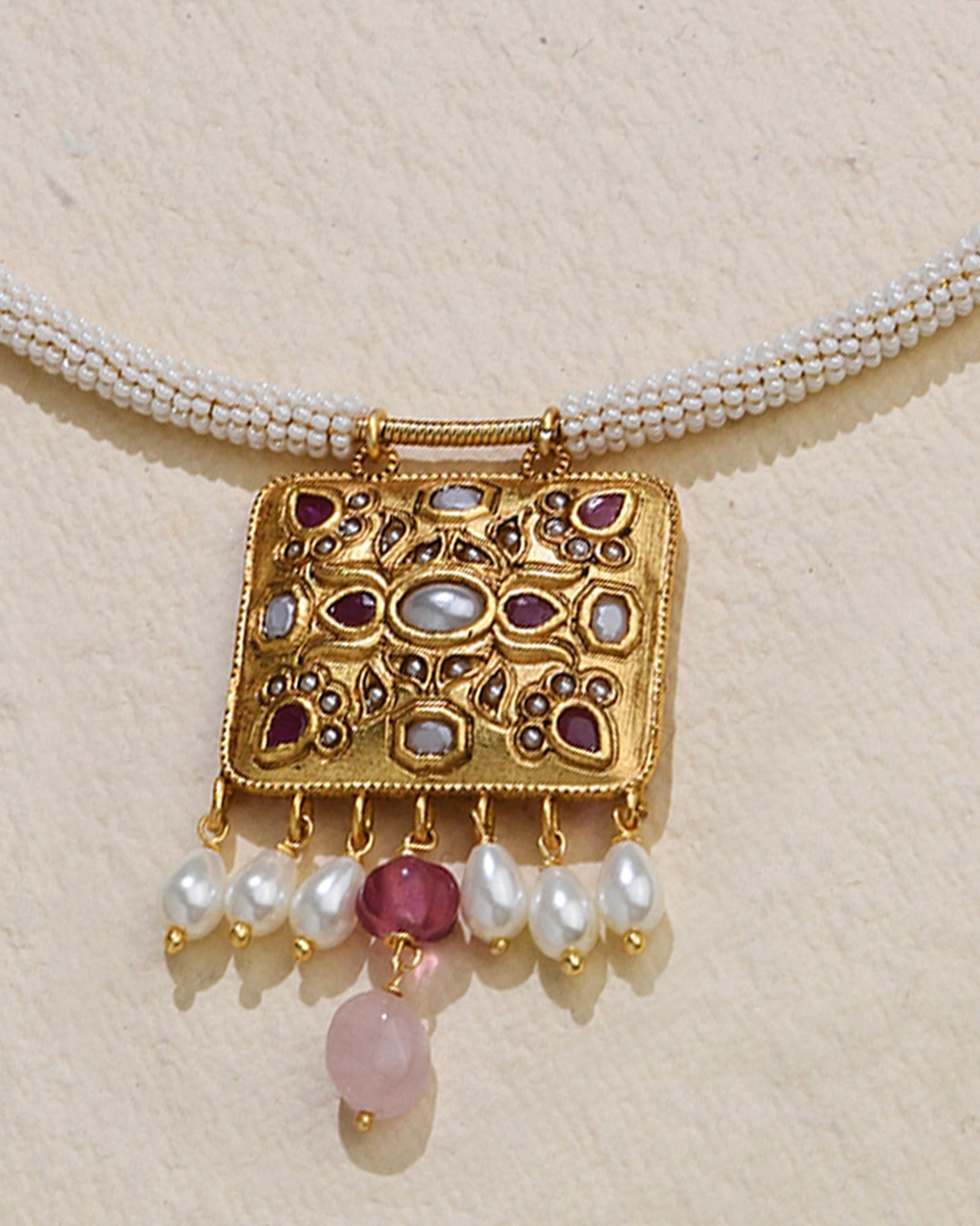 A golden wired necklace adorned with pearls and a pendant 