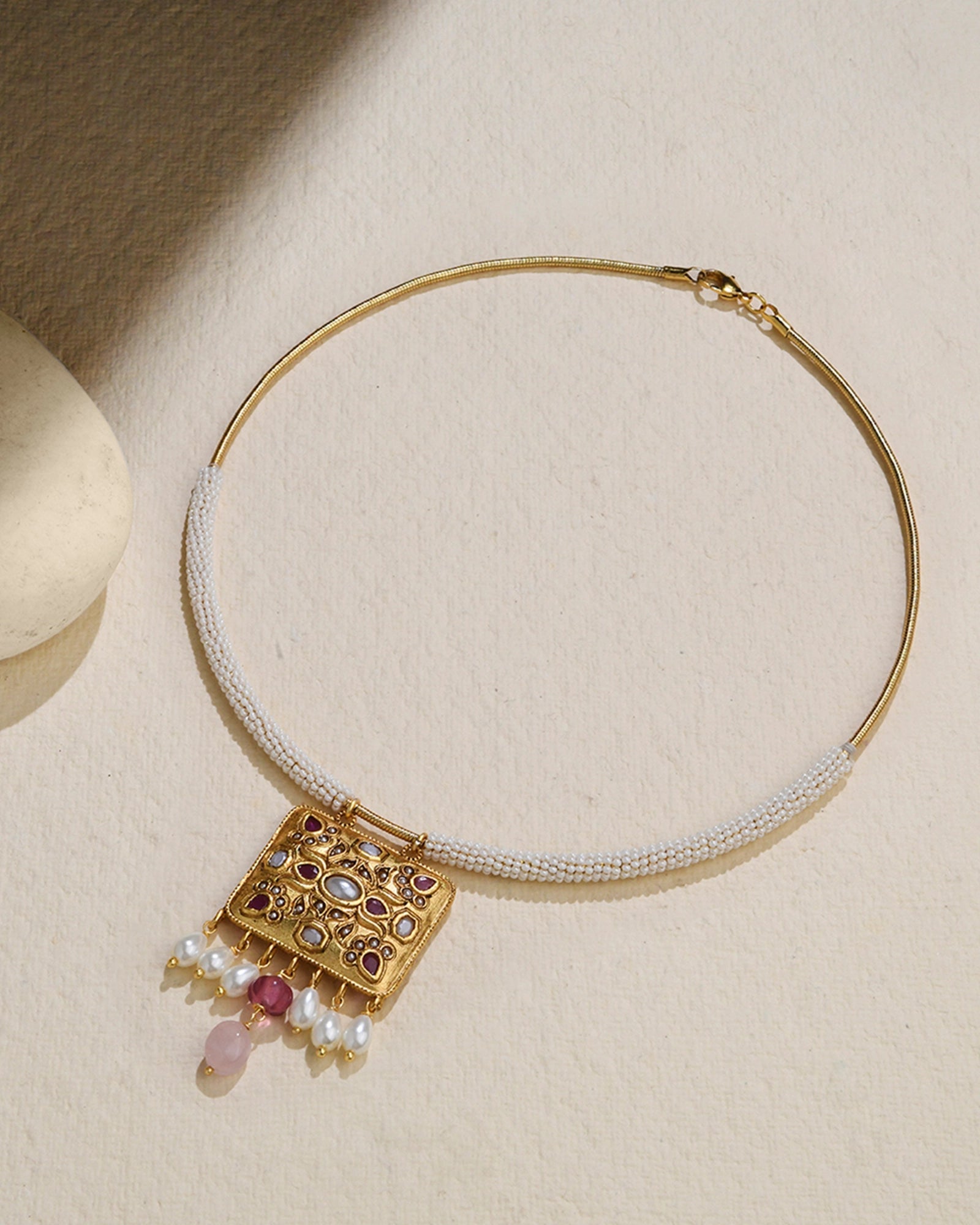 A golden wired necklace adorned with pearls and a pendant 